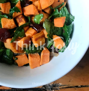 Roasted sweet potato and cranberries top wilted spinach to produce a sweet and savory warm salad