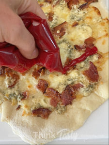 flatbread topped with bacon, blue cheese, and cranberry drizzle